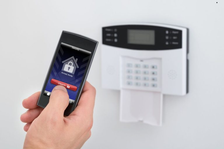 Individual using a smartphone to control a home alarm, highlighting modern home security technology.
